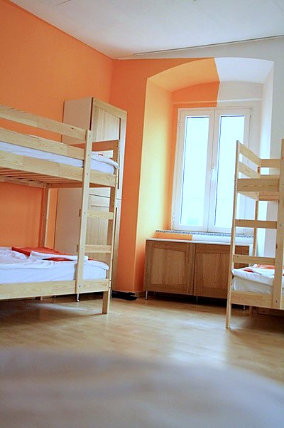 Narančasti zid osmerokrevetnog dorma s krevetom na kat uz prozor